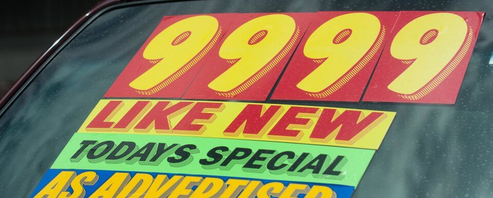 An add on the windshield of an used car that reads 9999 like new todays special as advertised to illustrate questions to ask when buying a used car.