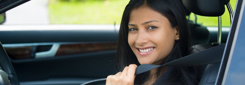 A young latino woman buckling up and ready to drive illustrates some safe-driving trips to consider.