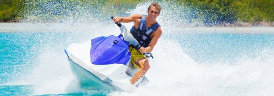 A young, Caucasian man riding a jetski and showcasing in which cases do I need insurance jetski personal watercraft.