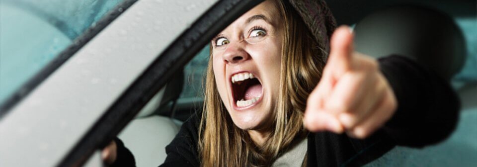 A young, Caucasian woman screams at the camera to illustrate tips to avoid aggressive driving and road rage.