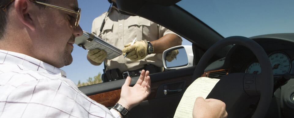 A driver who just received a ticket from a traffic officer illustrates traffic ticket myths debunked.