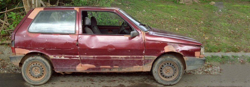 Photo of a beat up car with plenty of damage that illustrates when is it time for you and your car to part ways.