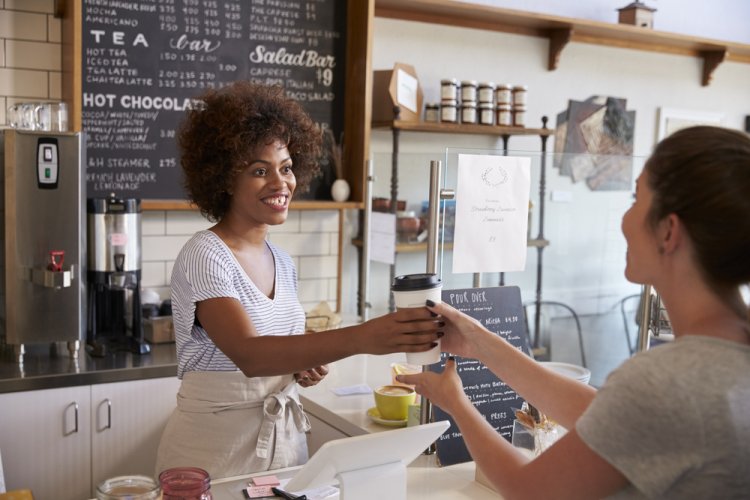 happy african american female cafe owner serving coffee to customer