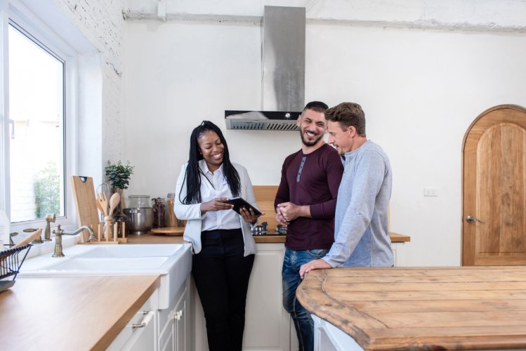 A landlady showing an apartment to a young couple who might need renter's insurance to rent it.