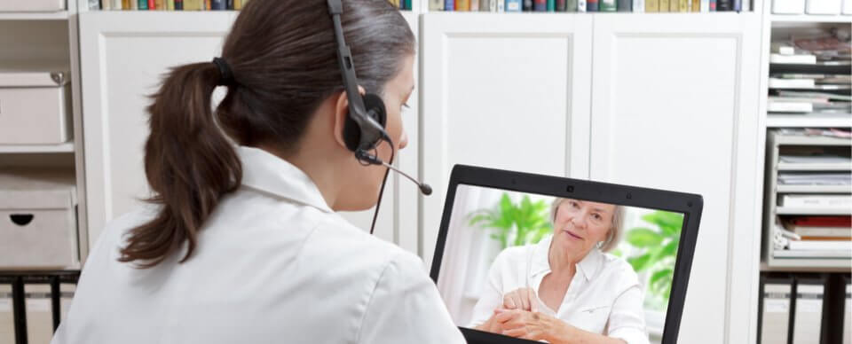 A middle-age physician giving medical advice to an elderly Caucasian woman over videoconference to portray the benefits of telemedicine.