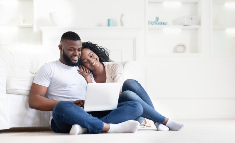 happy african american couple in home with laptop