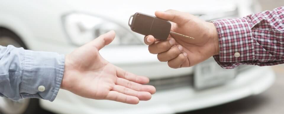 A man handing car keys to another person after a car sale to illustrate how to cancel insurance after selling car.