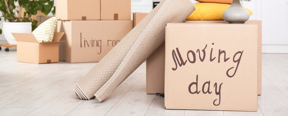 A pile of boxes that read moving day to illustrate the importance of transferring car insurance when you move out of state.