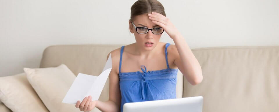 A worried woman looking at her penalties for no health insurance in 2020 in California.