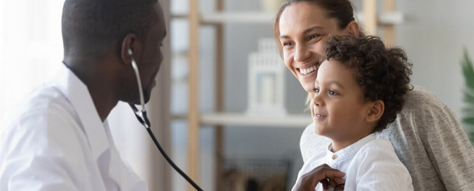 An African-American physician giving medical care to a Caucasian child thanks to his parent's health insurance subsidy.