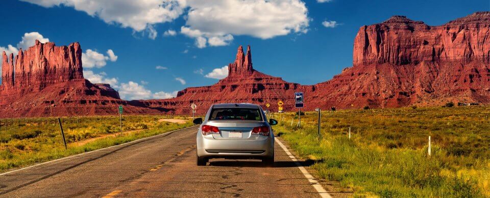 A car driving down a lonely road in the Arizona desert to illustrate the new Arizona car insurance requirements.