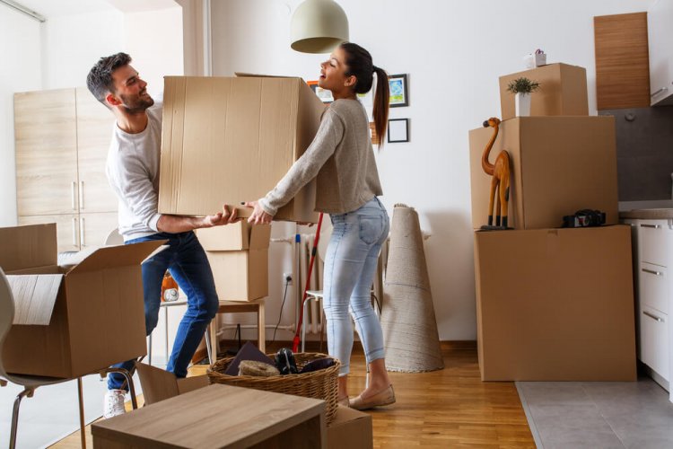 A young couple moving boxes in a newly-rented apartment after purchasing renters insurance