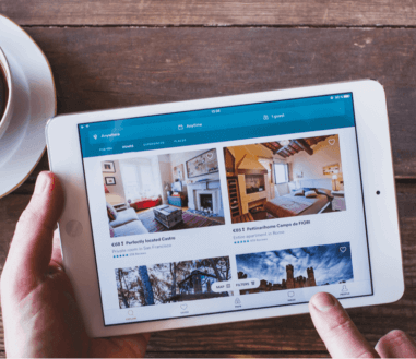 Two hands selecting a home-sharing room in a tablet to illustrate when do I need home-sharing insurance.