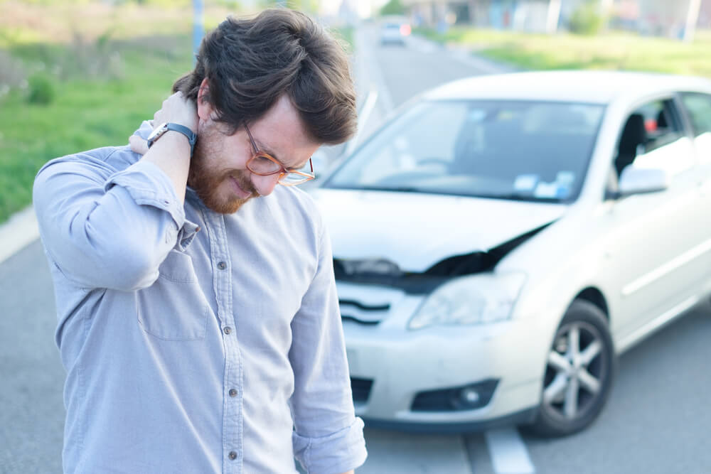 hurt man grabbing his neck in front of crashed car hit and run