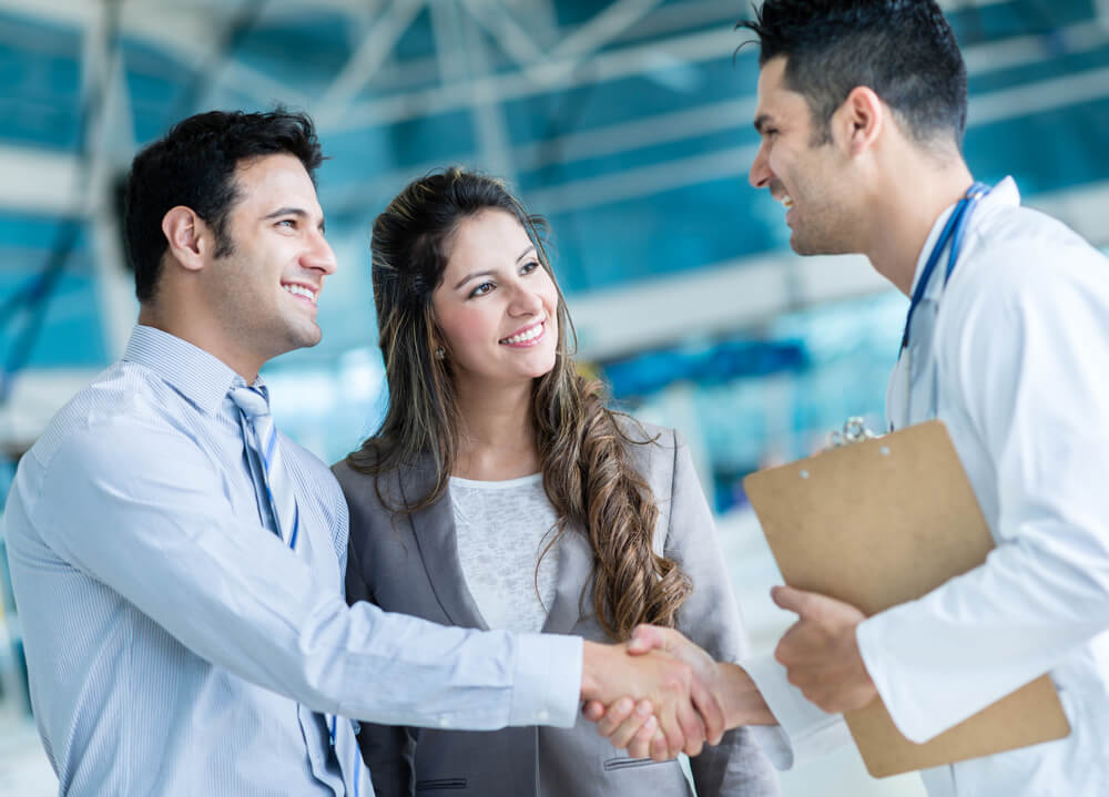 happy couple shaking hands with doctor indemnity plan insurance