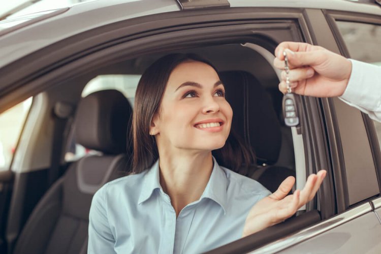 A young, Caucasian woman receiving car keys from a friend who lent the car to her to illustrate what is non-owner's car insurance