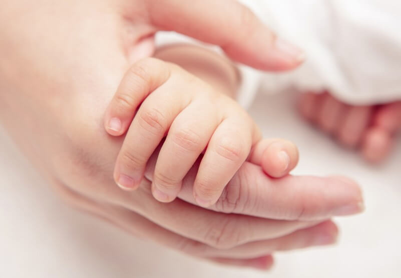 baby hand holding adult hand newborn insurance