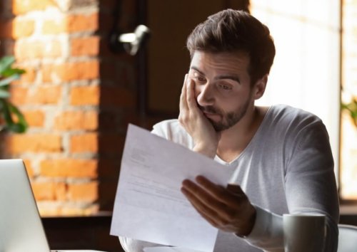 A worried young man looking at a policy because he lacks pandemic business interruption insurance.