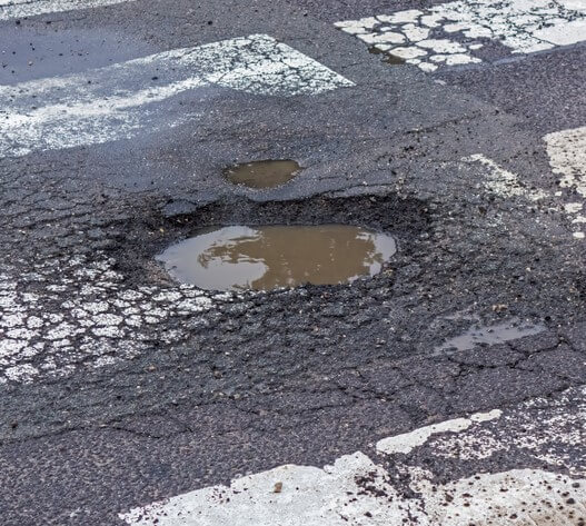 A pothole can damage your car. Remember to report and repair potholes on the road.