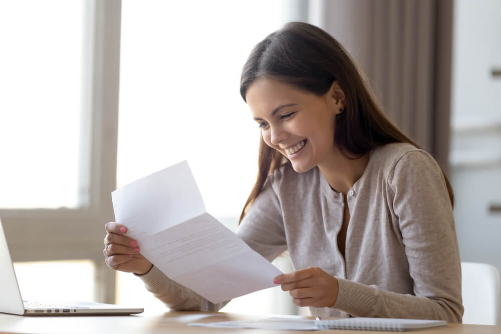 smiling woman reading a letter while social distancing
