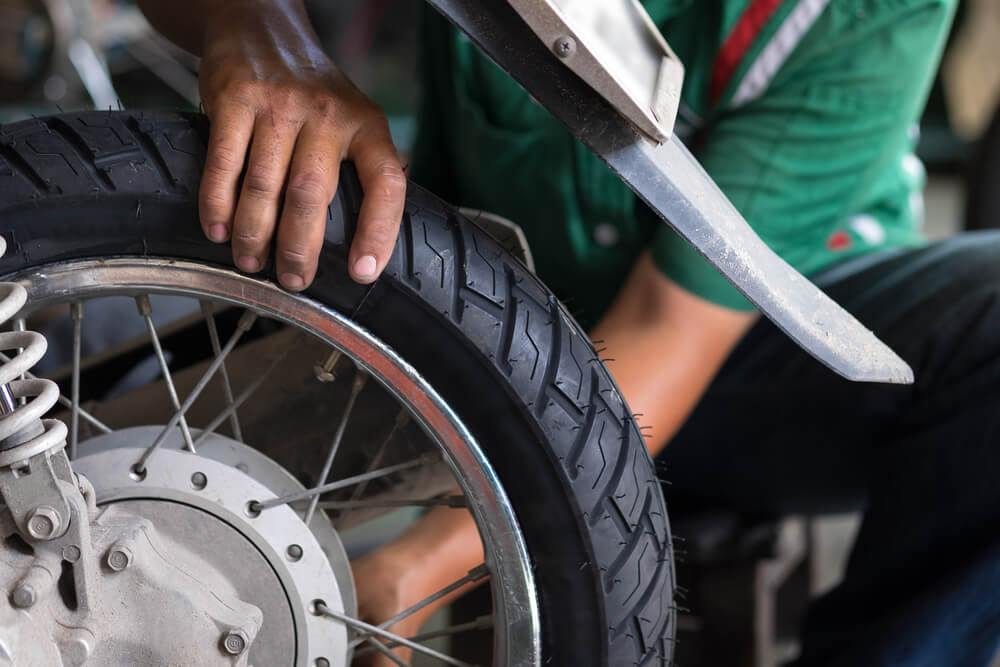 man checking the tires on his motorcycle for maintance