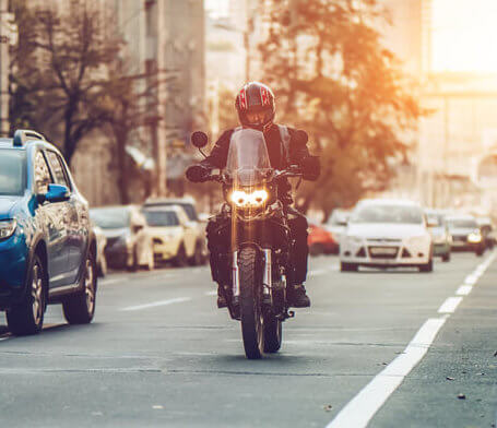 A motorcycle rider driving on city street. He is safe thanks to his antitheft device.