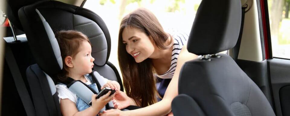 mother putting child in car seat to prevent hot car death