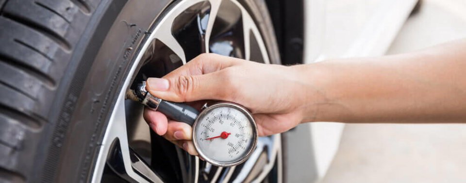 hand with tire pressure gauge checking tire