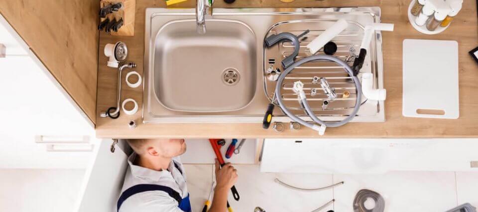 plumber fixing a kitchen zinc with homeowners insurance