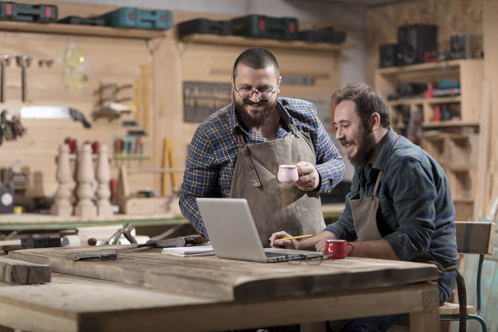 woodworkers at their shop looking at a business insurance policy in a laptop