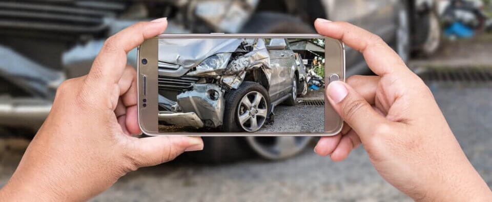 hands with a cell phone taking a picture of an underinsured motorist car accident