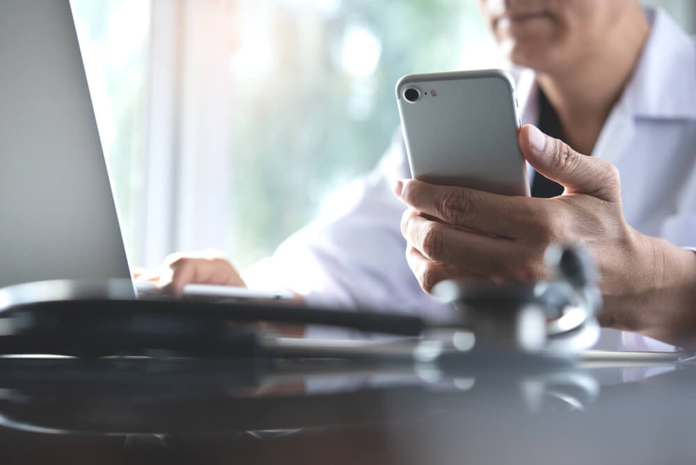 doctor with phone seeing patients with telemedicine and medical technology