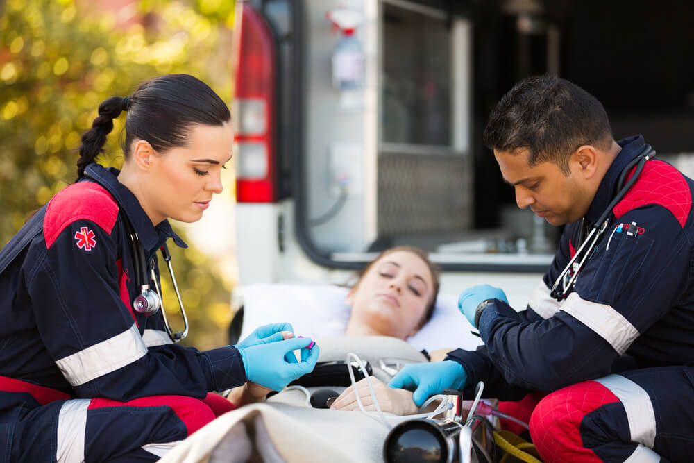 paramedics helping patients with add insurance in front of ambulance