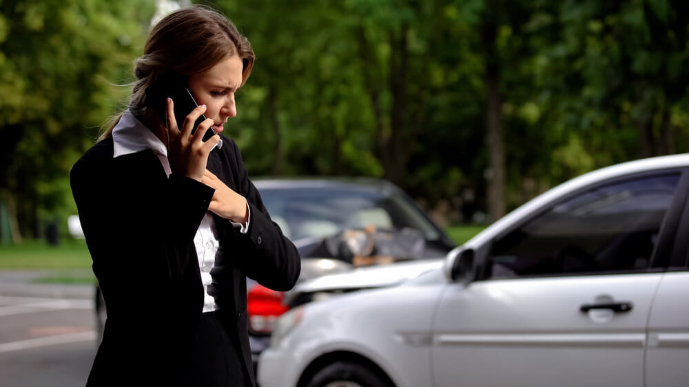 worried woman using her phone after a car accident with an uninsured driver