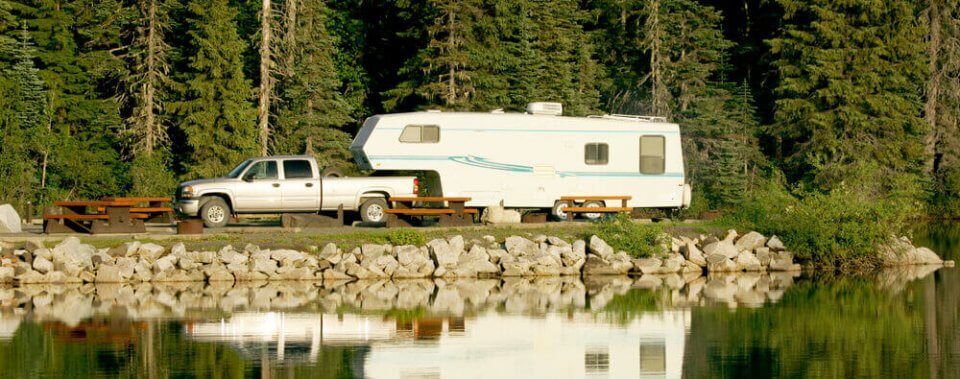 fifth wheel camper parked next to a lake