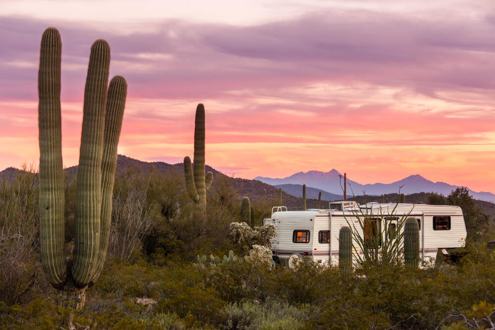 fifth wheel camper parked in the desert during a sunset