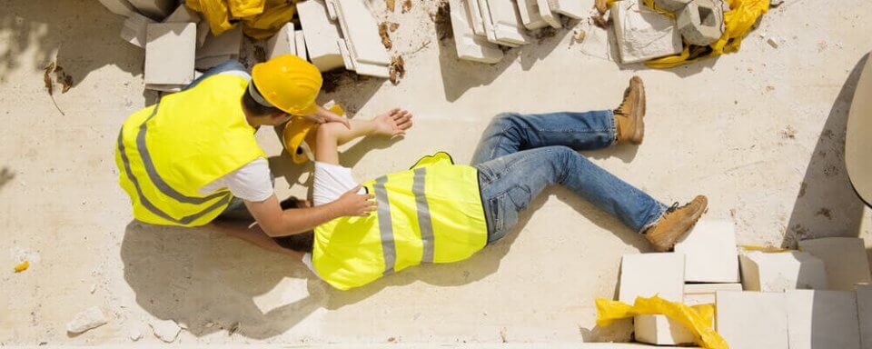accident in construction site with a fallen man and another tending to him