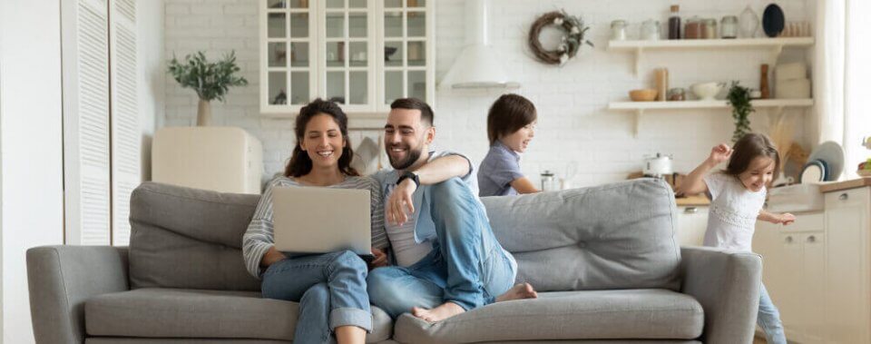 happy couple sitting on their living room on their rental home with kids running around
