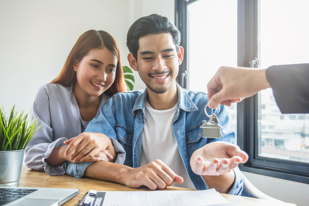 happy couple of renters getting their keys from their landlord