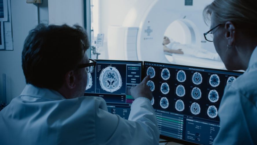 A radiographer checks the scans of a patient undergoing a CT scan.