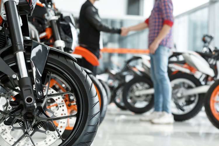 motorcycle in the forefront in a bike shop with two people in the background