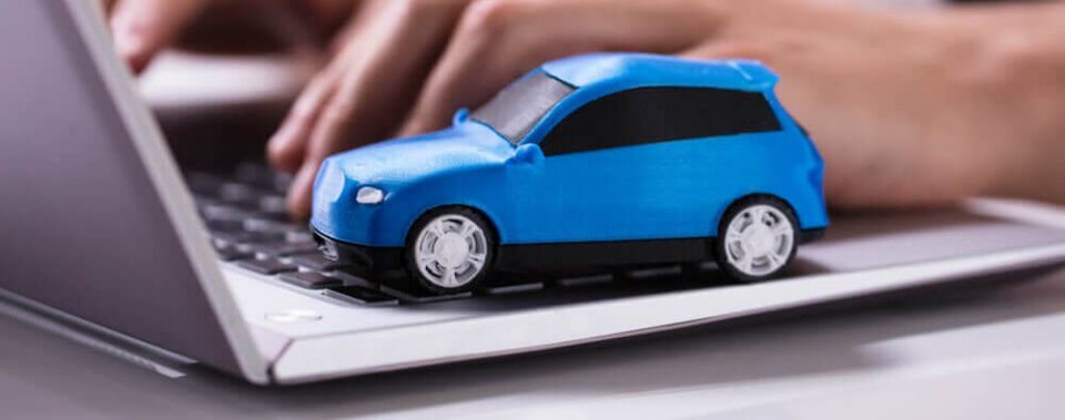 toy car on laptop with a person typing on it looking for car insurance