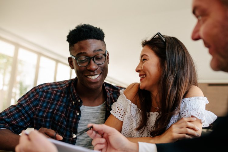 A happy interracial couple signing a contract and renting for the first time.