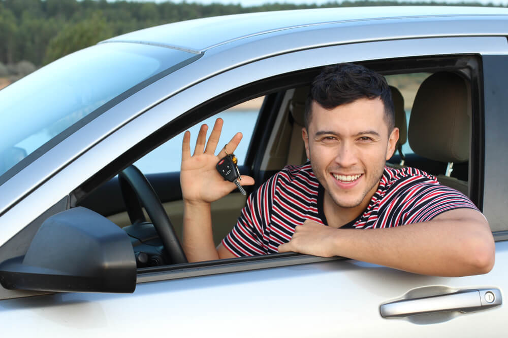 happy young man holding keys ready to buy a used car