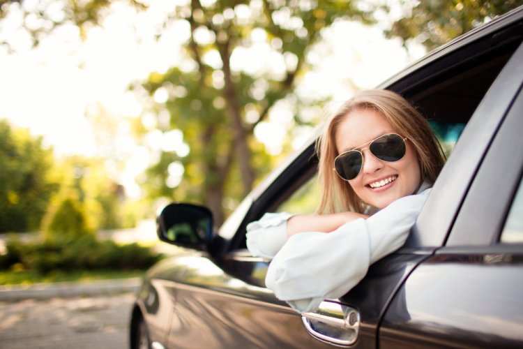 smiling woman sitting on the front seat of a car