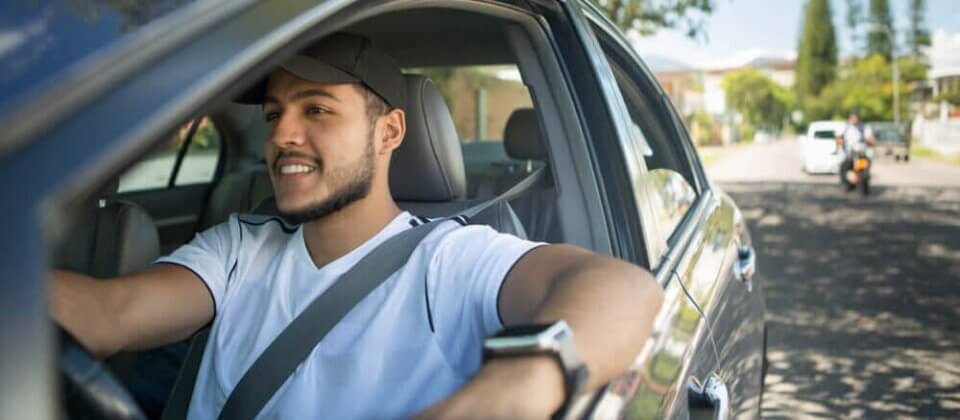 Photography of a man smiling as he drives his car.