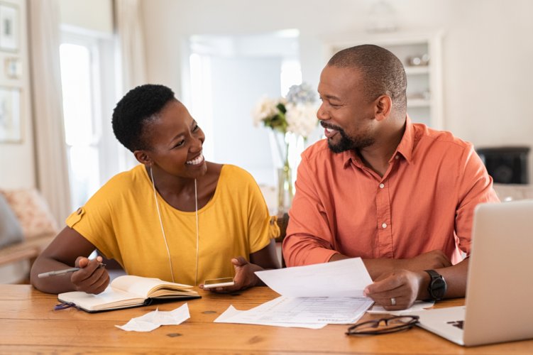 happy african american couple looking at tablet during open enrollment 2021