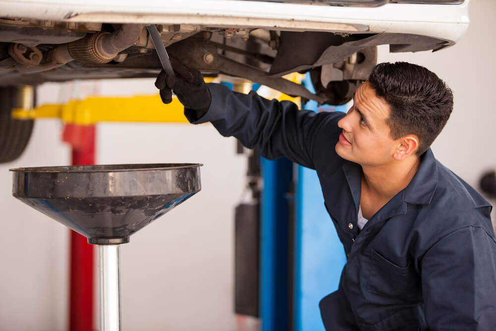 mechanic changing the oil on car in his shop to take care of it