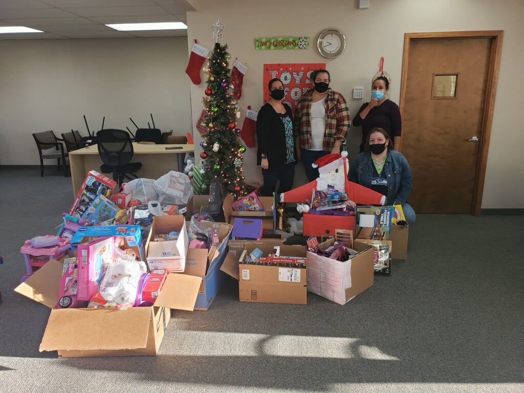 group of happy people in office with toys for tots donations