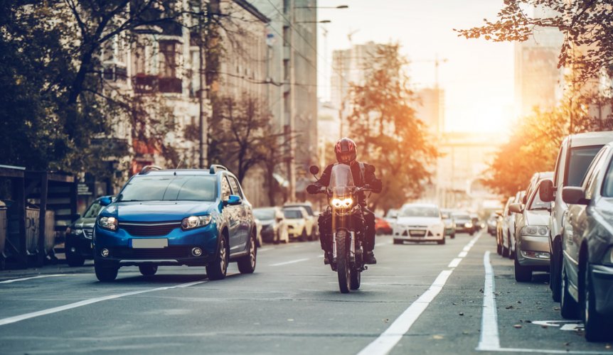 Traffic on a busy street with cars and a motorcycle to illustrate cheap motorcycle insurance.